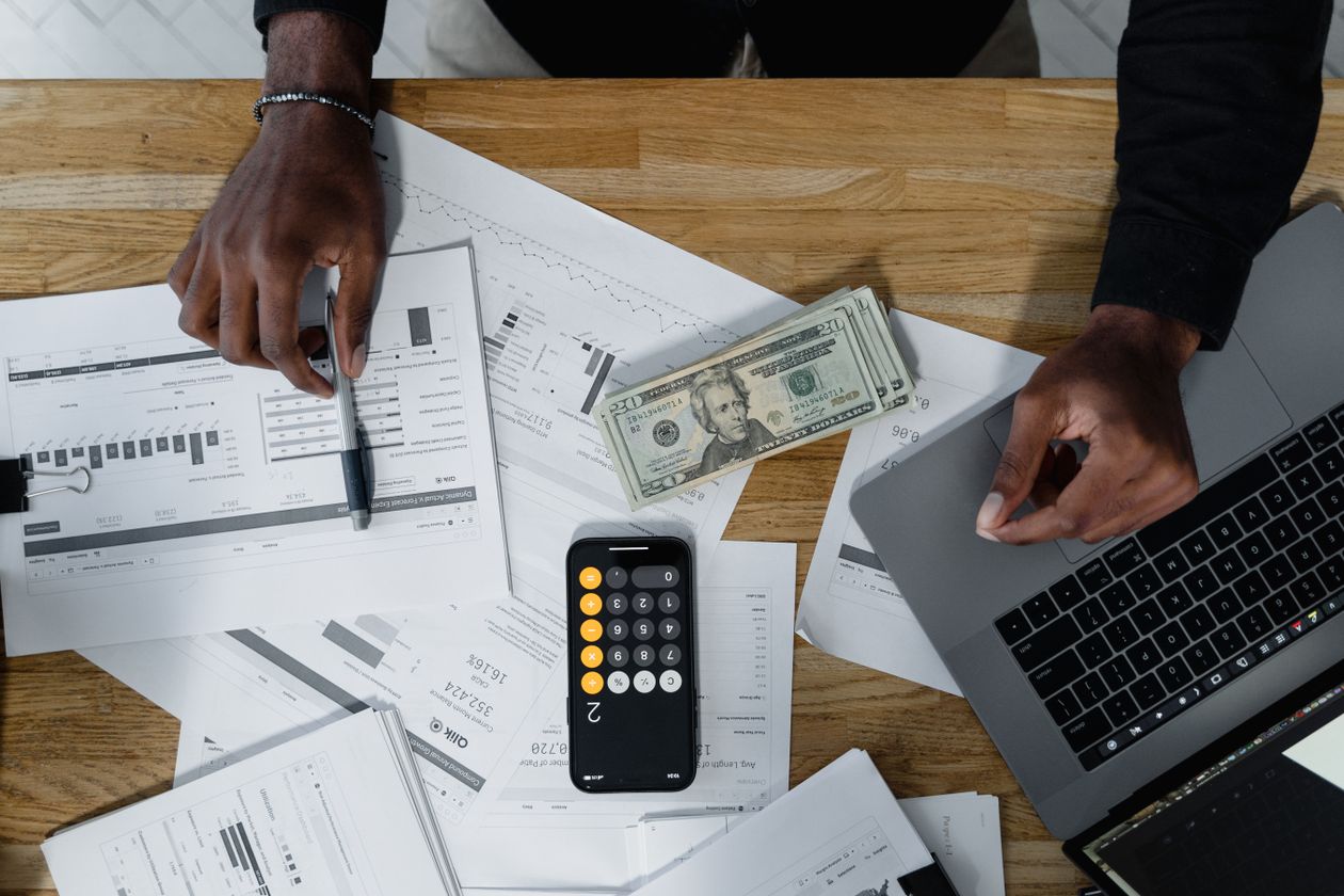 Manos profesionales revisando papeles y planillas contables con calculadora
