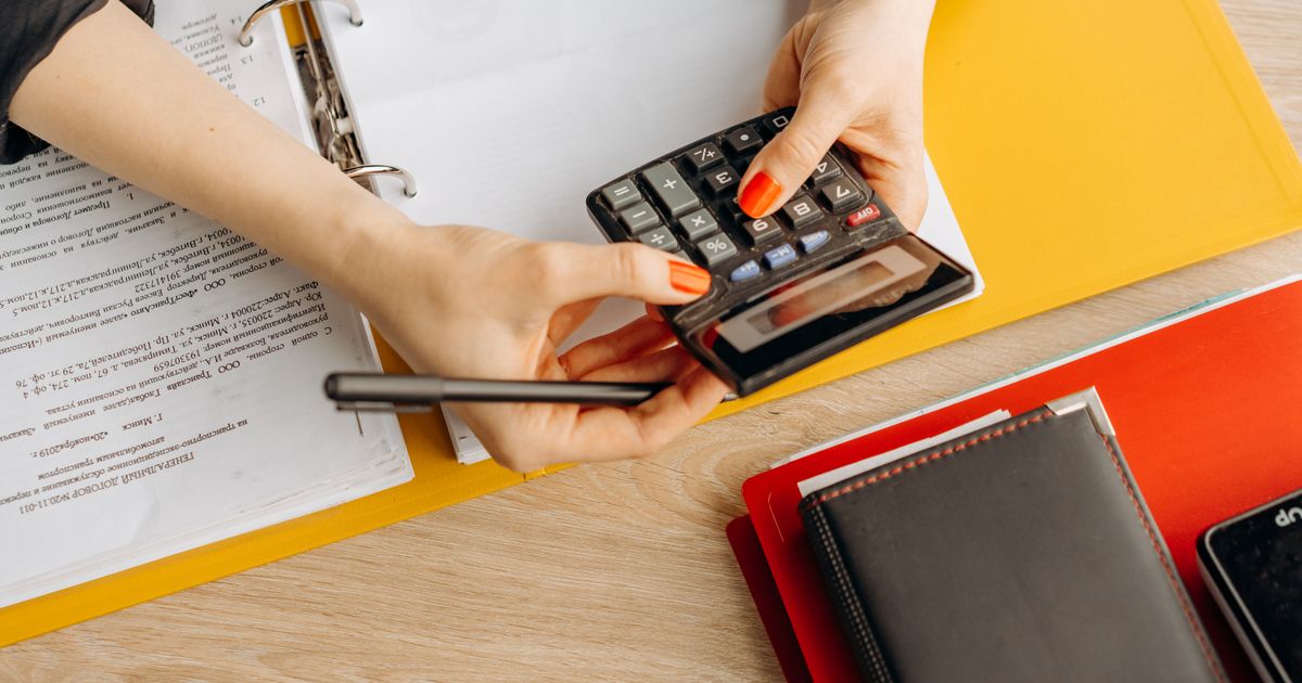Manos usando una calculadora sobre un escritorio con documentos y carpetas contables