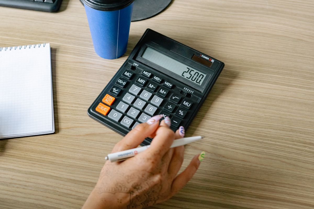 Calculadora y lapicera sobre un escritorio de madera, revisando comprobantes emitidos